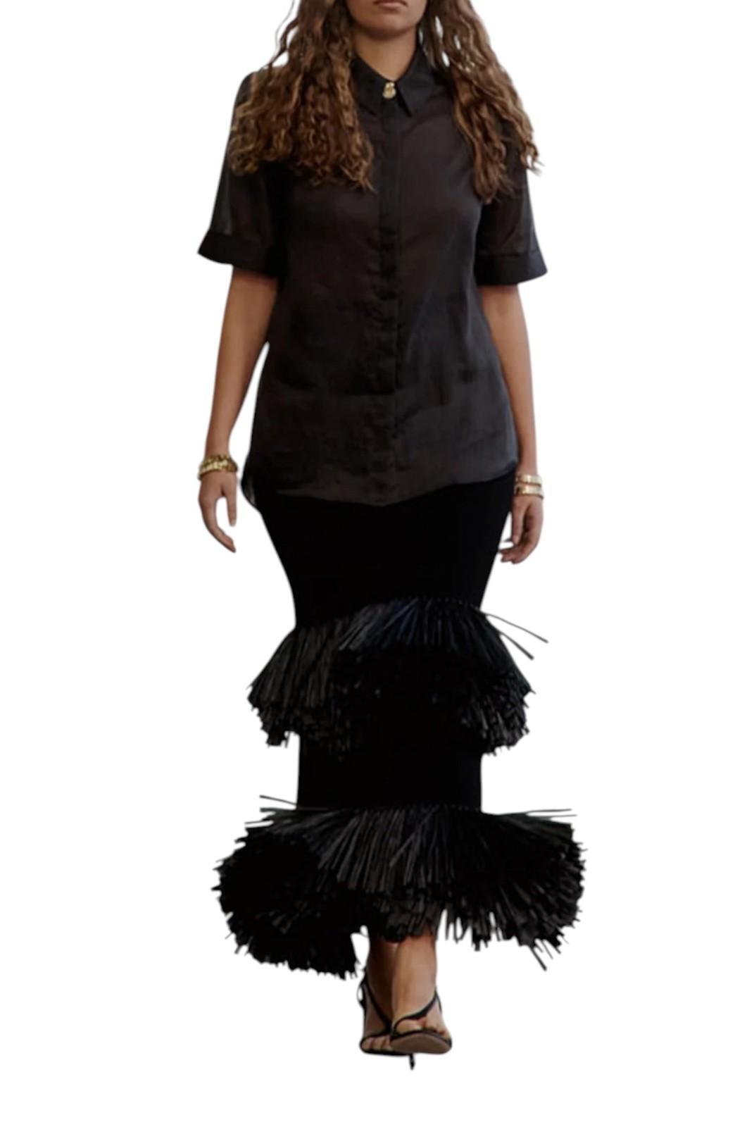 Woman wearing a black blouse with a ruffled black skirt on a white background