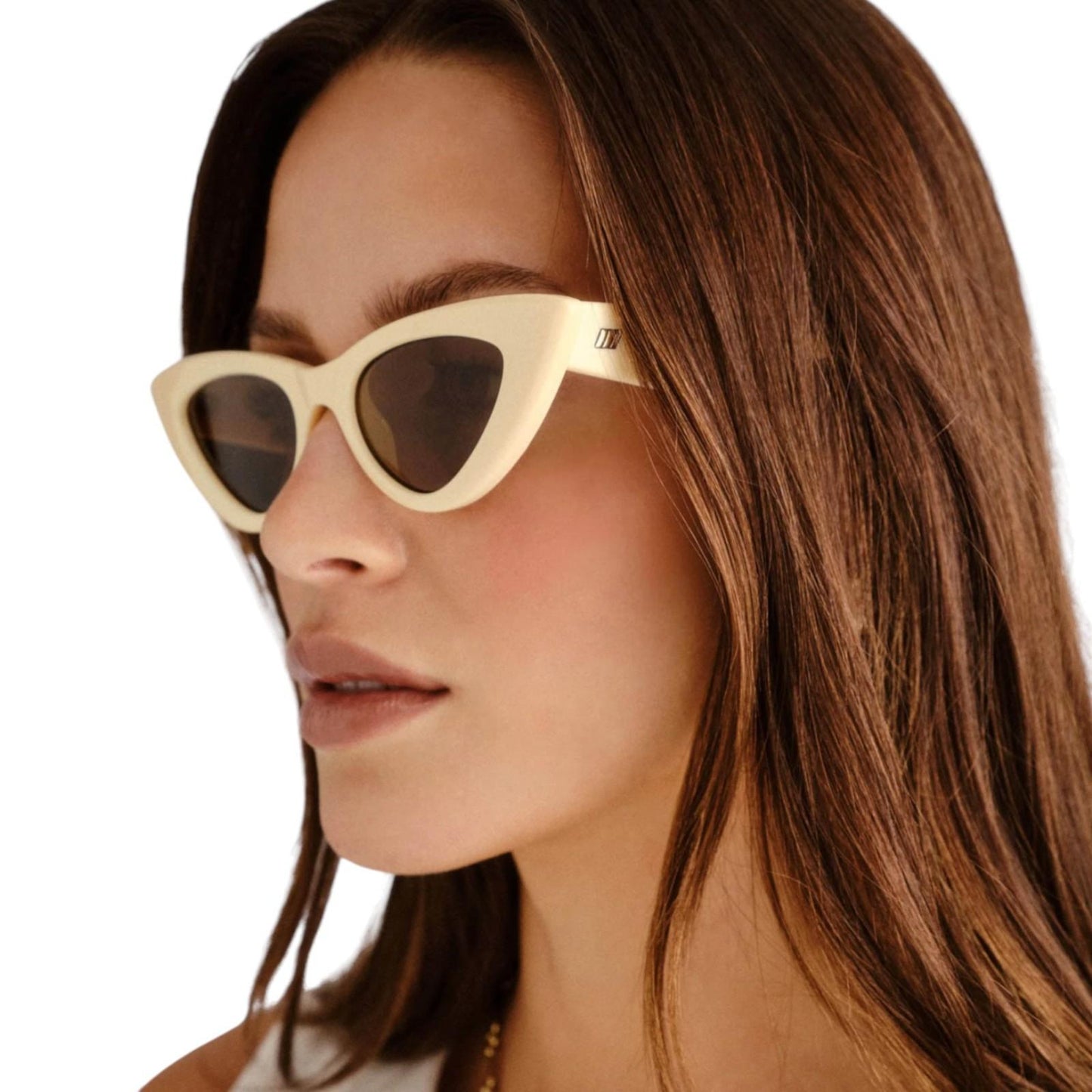 Close-up of a person wearing beige cat-eye sunglasses with a plain background