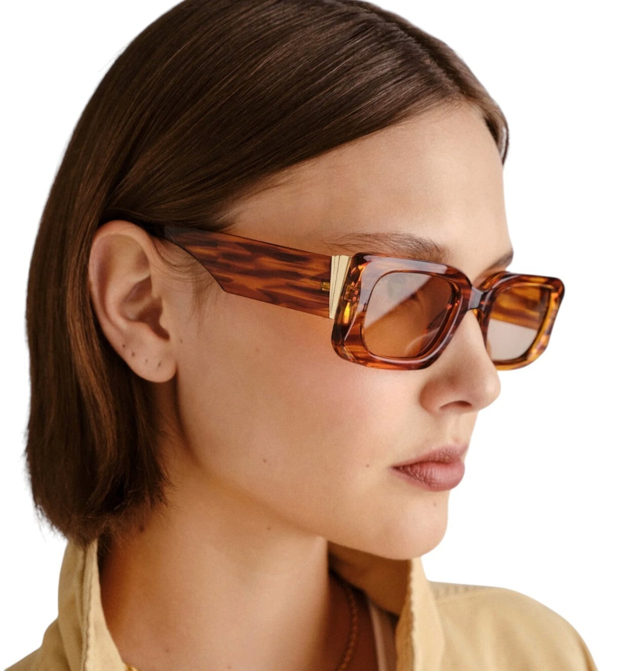 Close-up of a person wearing tortoiseshell sunglasses with a neutral background