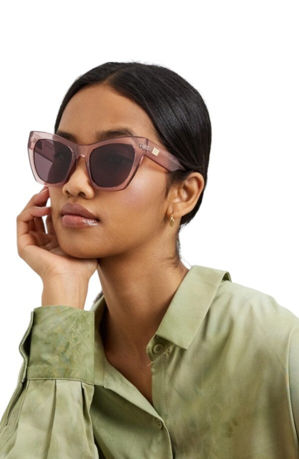 Woman wearing pink sunglasses and a green shirt on a white background