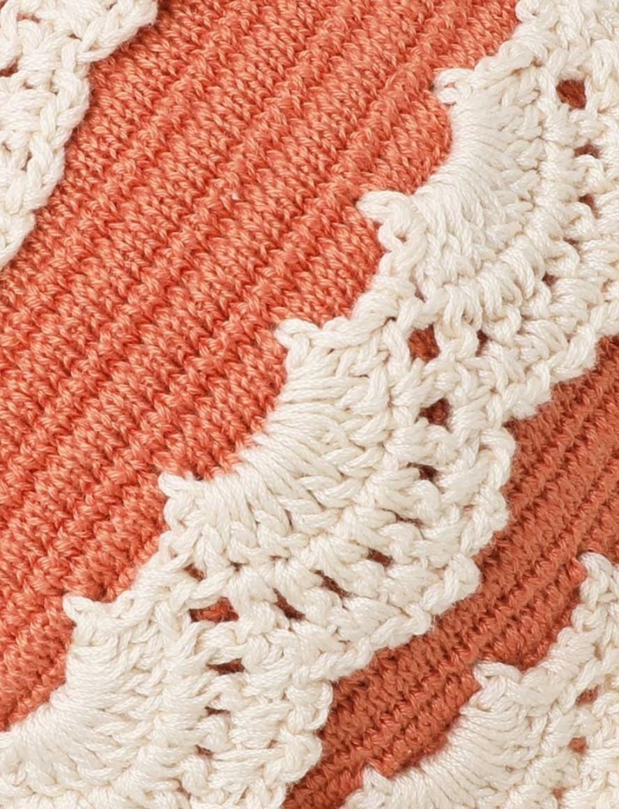 Close-up of a textured fabric with a white lace trim on a red background
