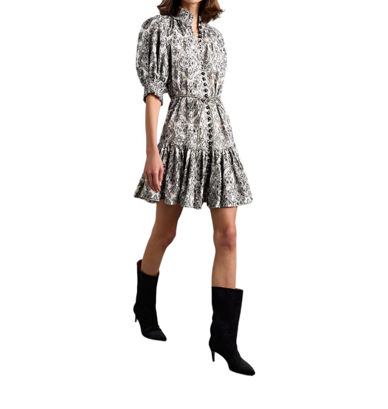 Woman wearing a black and white patterned dress with black boots on a white background
