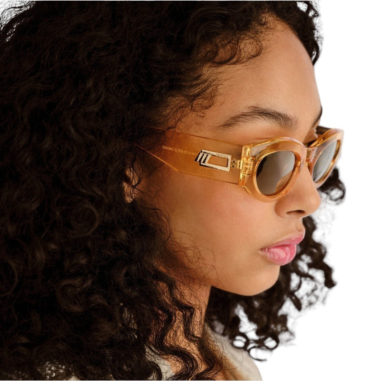 Woman wearing gold-framed sunglasses with a white background