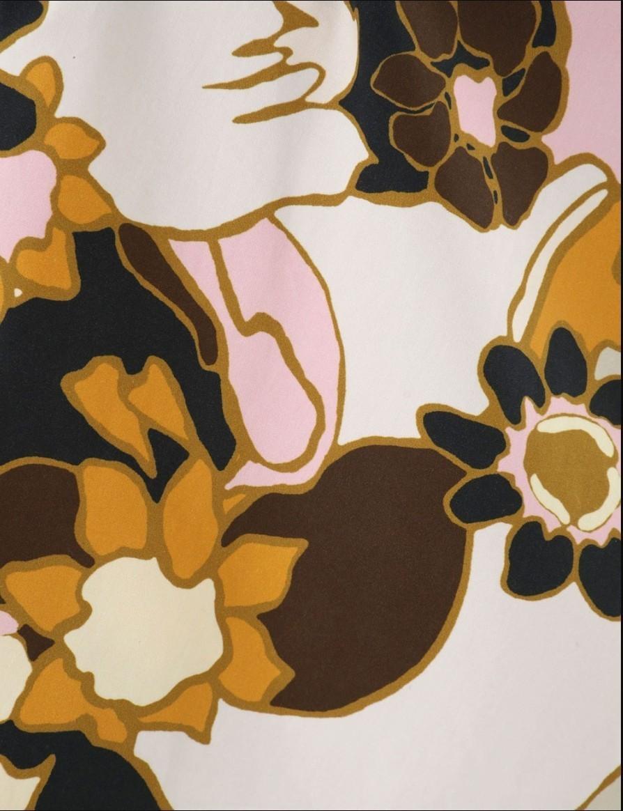 Close-up of a floral pattern with brown, orange, and pink colors on a light background.