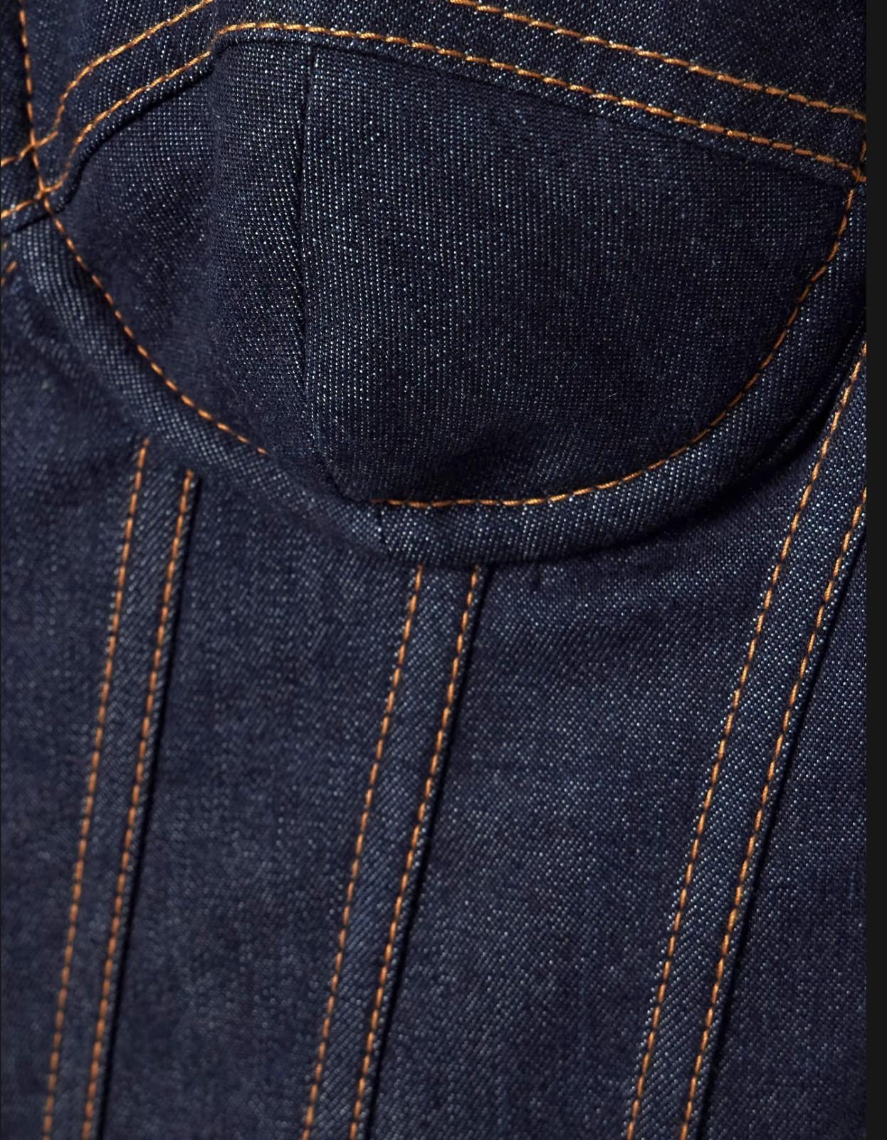 Close-up of dark blue denim fabric with brown stitching