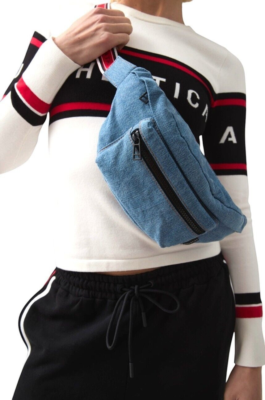 Naked Pear Aje. Athletica denim crossbody bag in coastside blue with a red, black, and white logo adjustable strap.