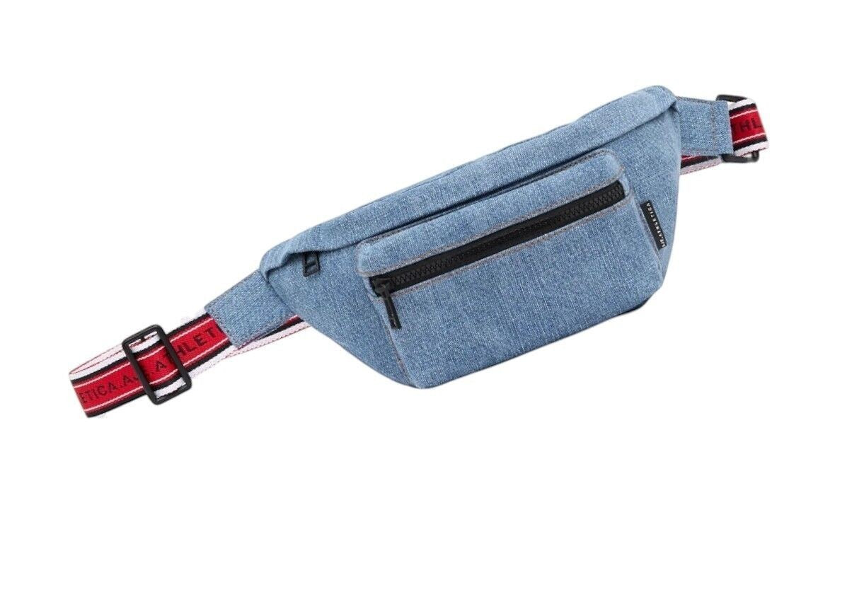 Naked Pear Aje. Athletica blue denim crossbody bag with an adjustable red, black, and white logo strap and zip pockets.
