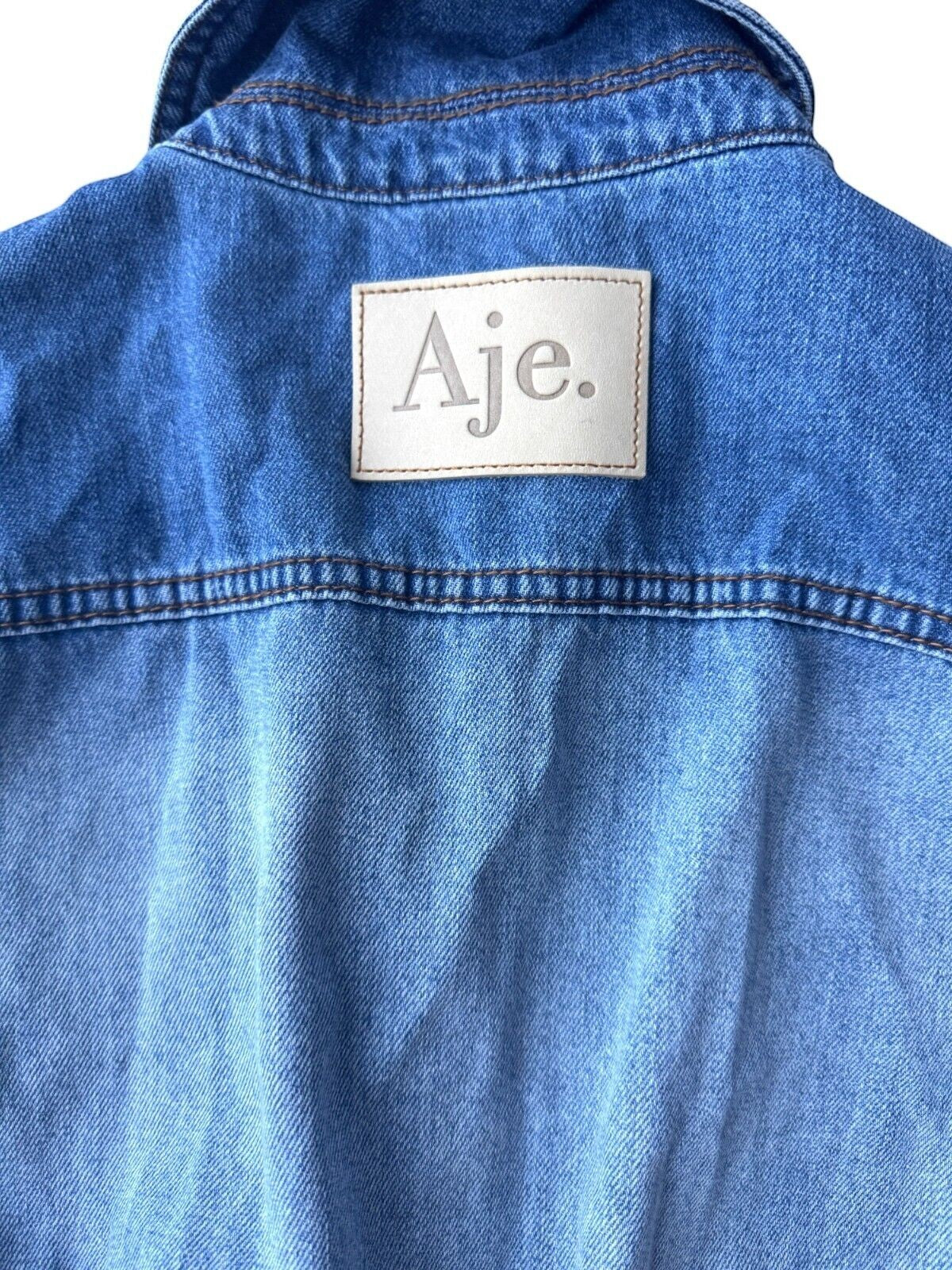 Naked Pear Aje Ines denim playsuit back view showing two-toned blue denim panels and branded leather label