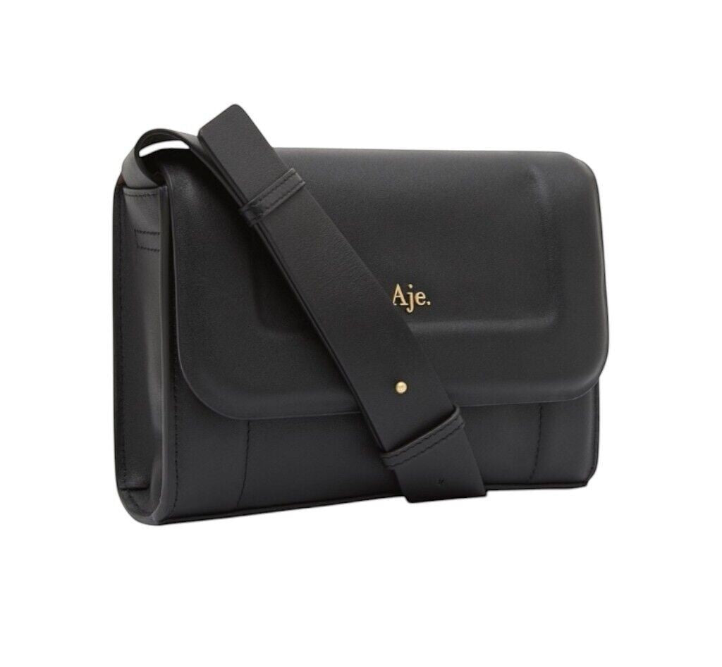 Naked Pear Aje Lora black cow leather crossbody bag with padded flap, adjustable strap, and gold logo detail.