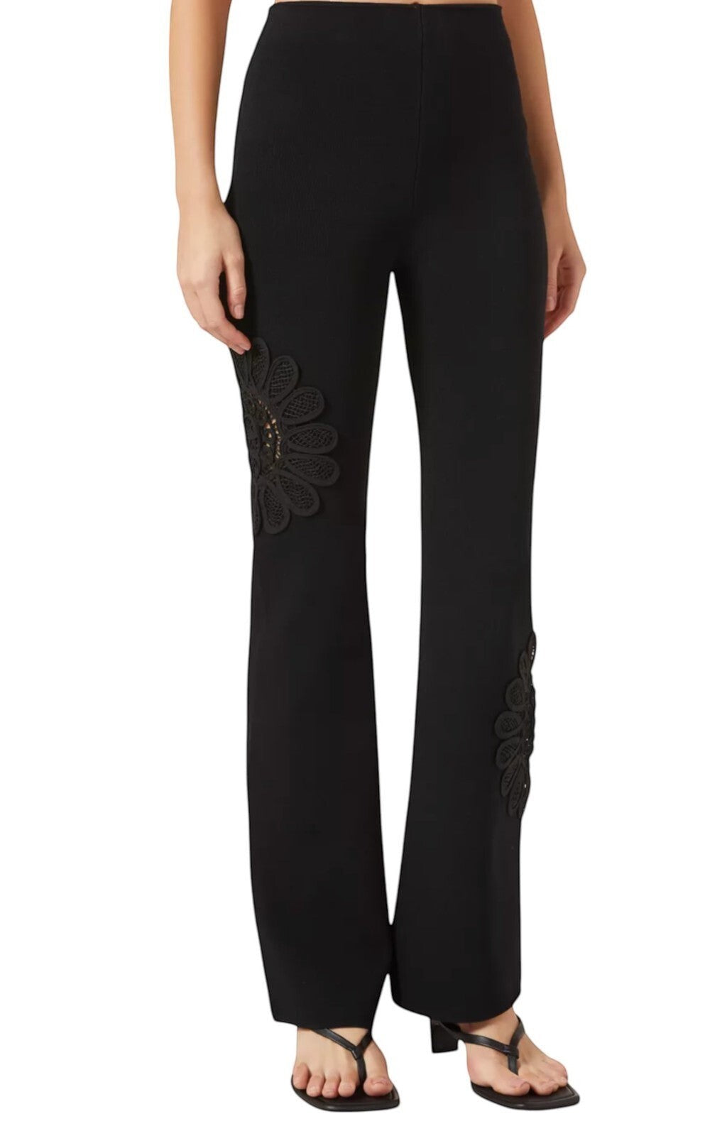 Naked Pear Aje black high-waisted knit pants featuring a flared silhouette and intricate lace flower leg detailing.