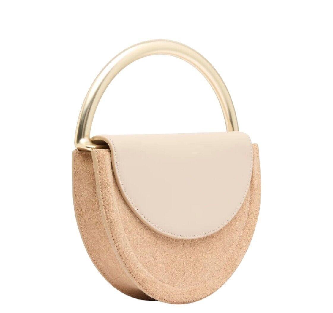 Naked Pear Aje Norma crescent crossbody bag in beige suede with a smooth leather flap and gold metal handle.