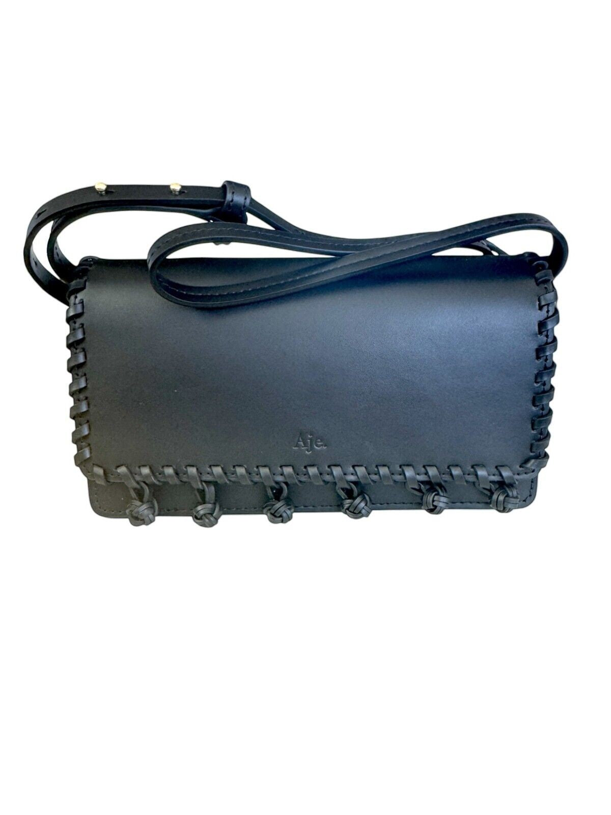 Naked Pear Aje black leather crossbody bag with tassel pom-pom trim, flap closure, and adjustable shoulder strap.
