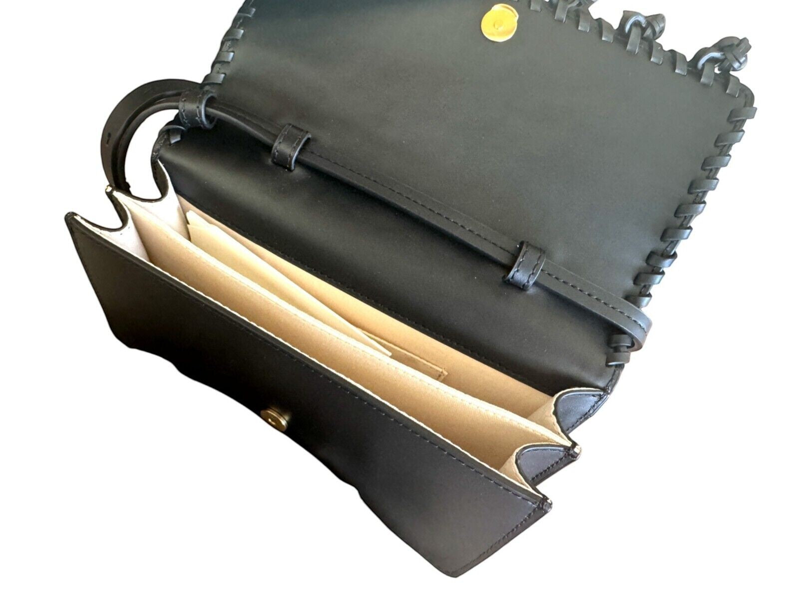 Naked Pear Aje black leather crossbody bag with open flap, twin compartments, and decorative pom-pom trim detail.