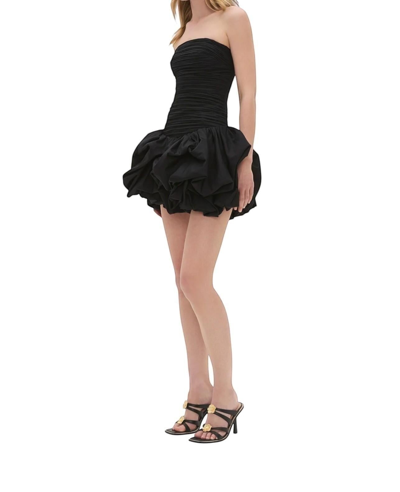 Naked Pear Aje black strapless mini dress with a ruched bodice and voluminous bubble hem skirt on a model