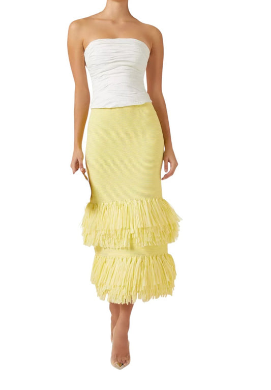 Woman wearing a white strapless top and yellow ruffled skirt on a white background
