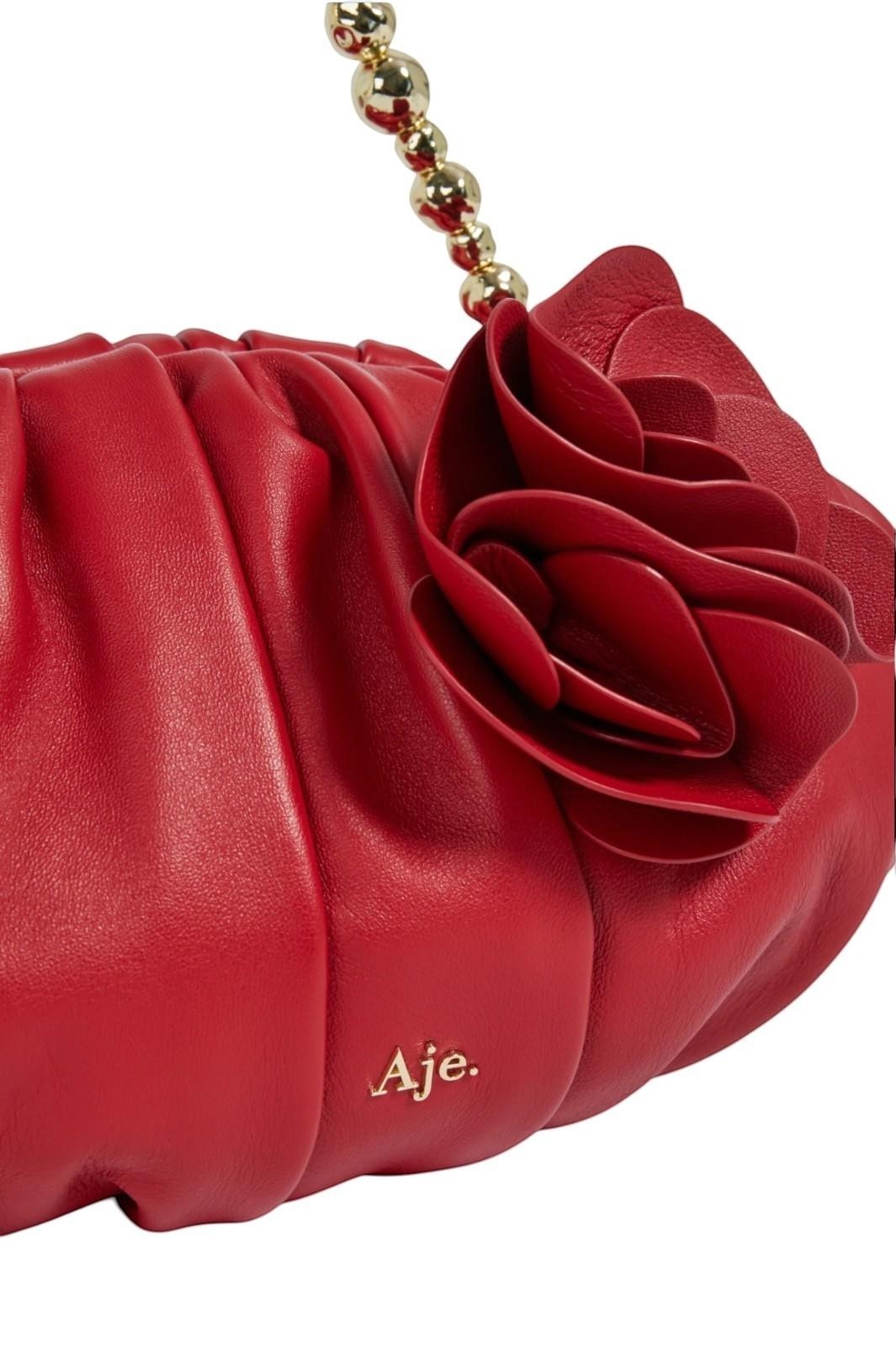 Red clutch bag with floral design and 'Aje.' branding on a white background