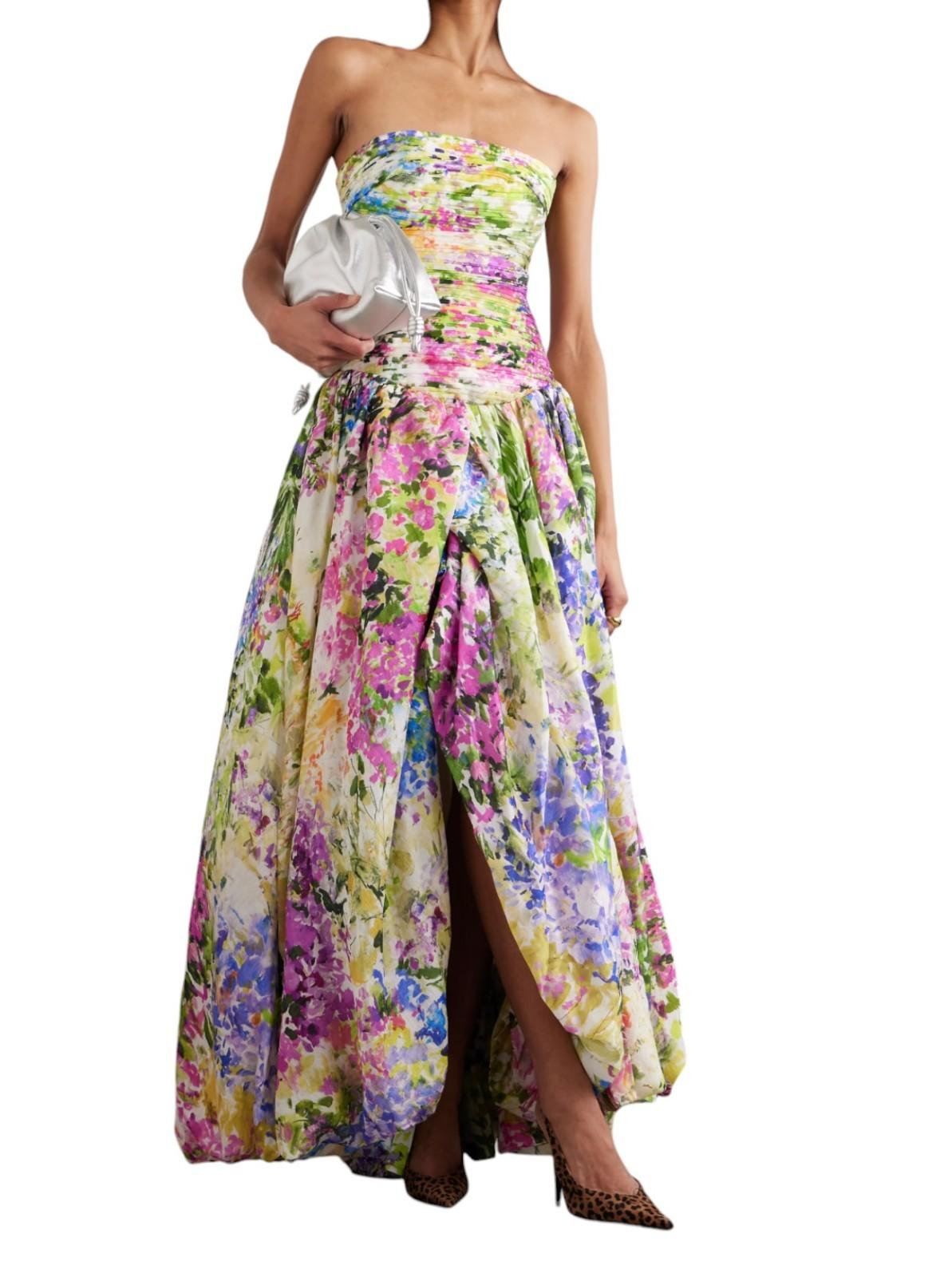 Woman wearing a strapless floral gown with a slit on a white background