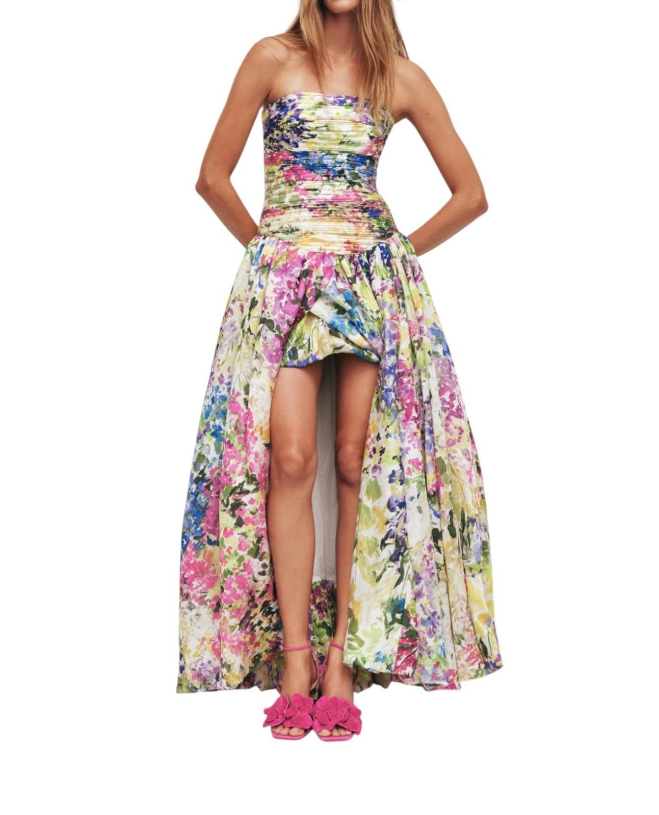 Woman wearing a colorful floral dress with a slit on a white background