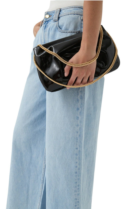 Person holding a black clutch with gold handle against a white background