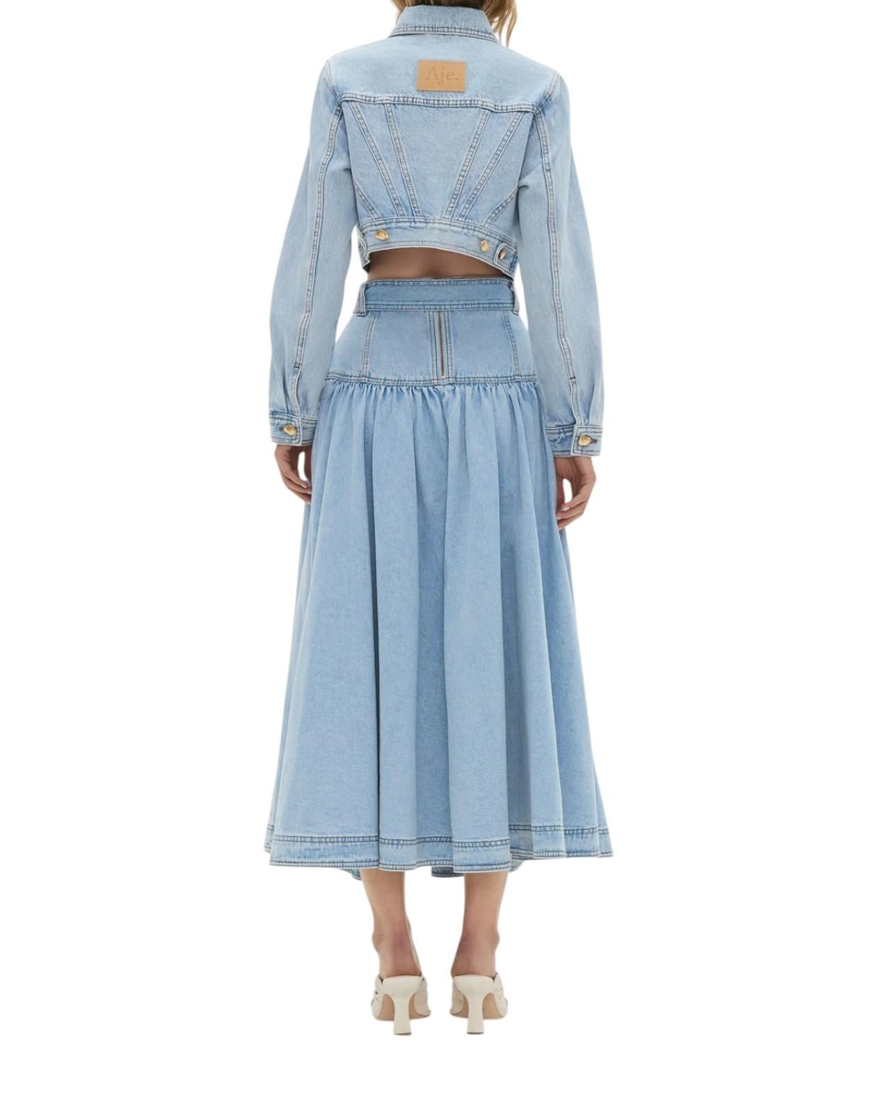Person wearing a light blue denim jacket and skirt set on a white background
