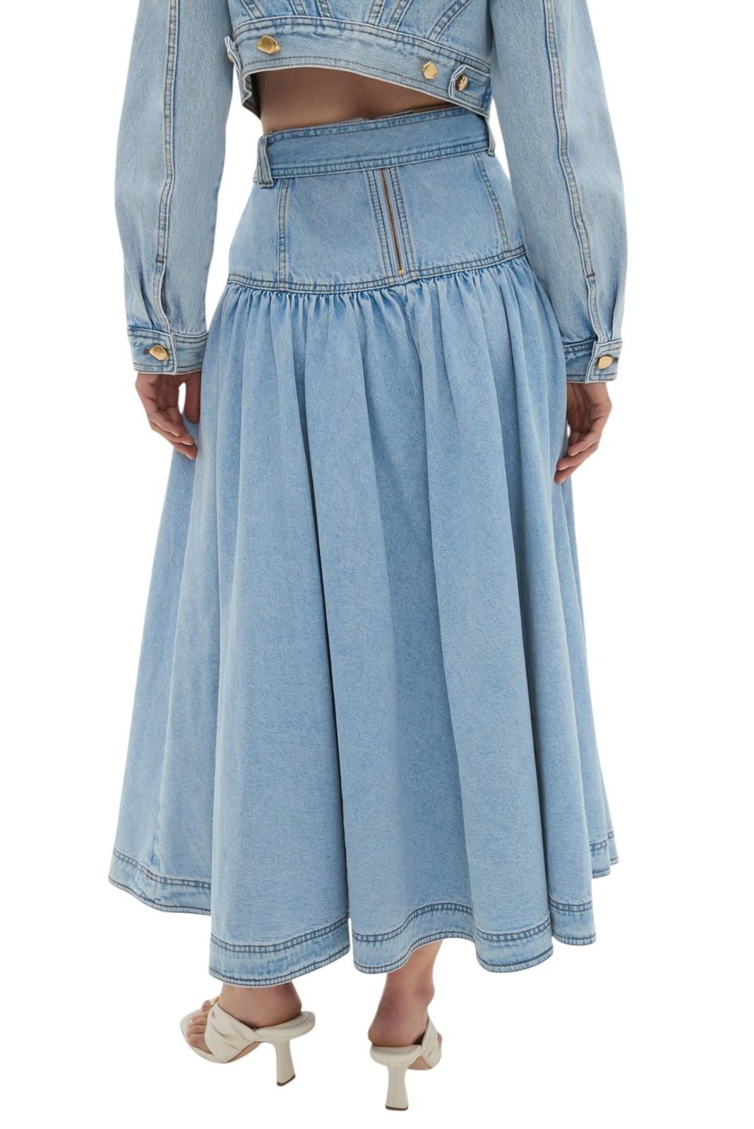 Person wearing a light blue denim skirt and jacket on a white background