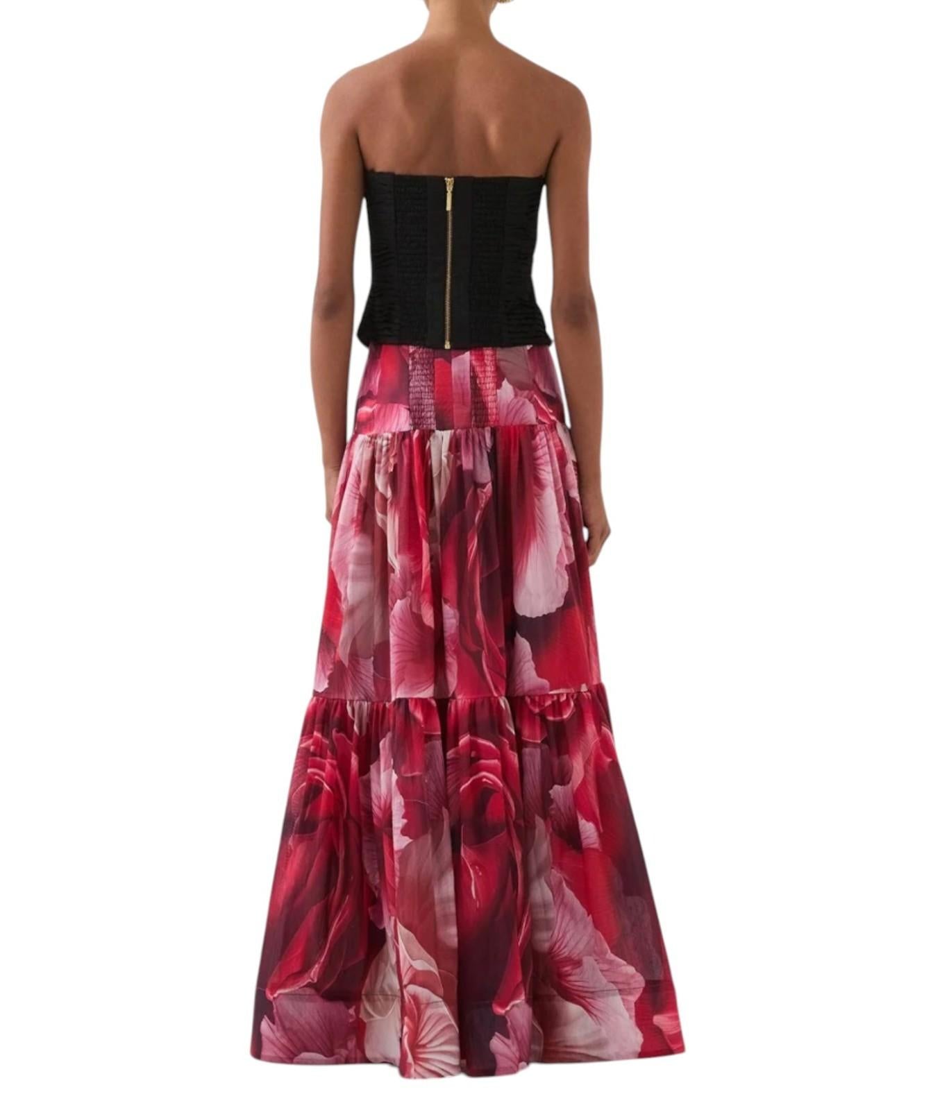 Woman wearing a strapless black top and red floral skirt on a white background