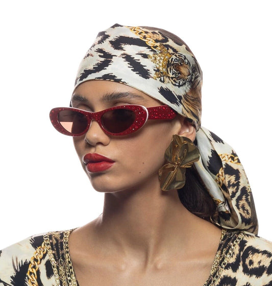 A model wearing red/white cat-eye sunglasses with red crystals and a leopard print headwrap.
