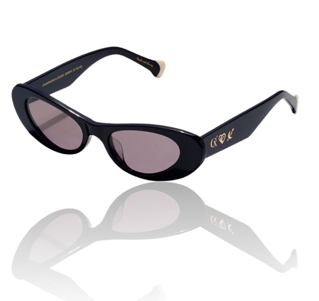 A pair of black, cats eye sunglasses with gold foil detailing and a signature gold tip shape on the arms.