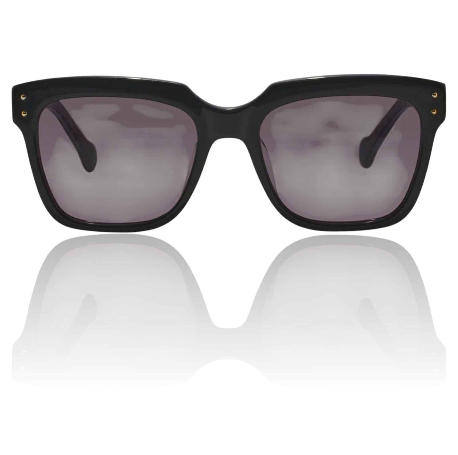 Black sunglasses with dark lenses on a reflective white surface