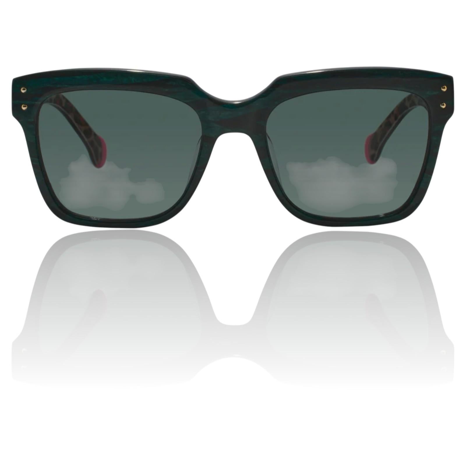 Sunglasses with dark lenses and green frames on a reflective white surface