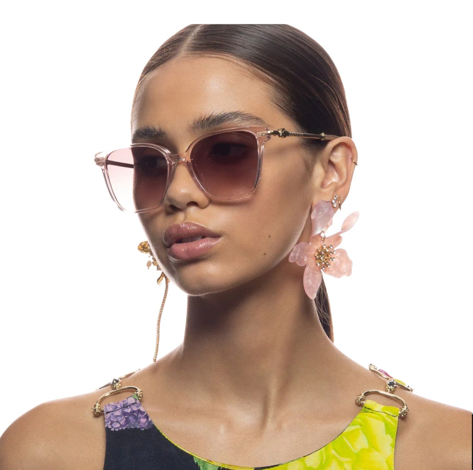 Woman wearing sunglasses and floral earrings on a white background