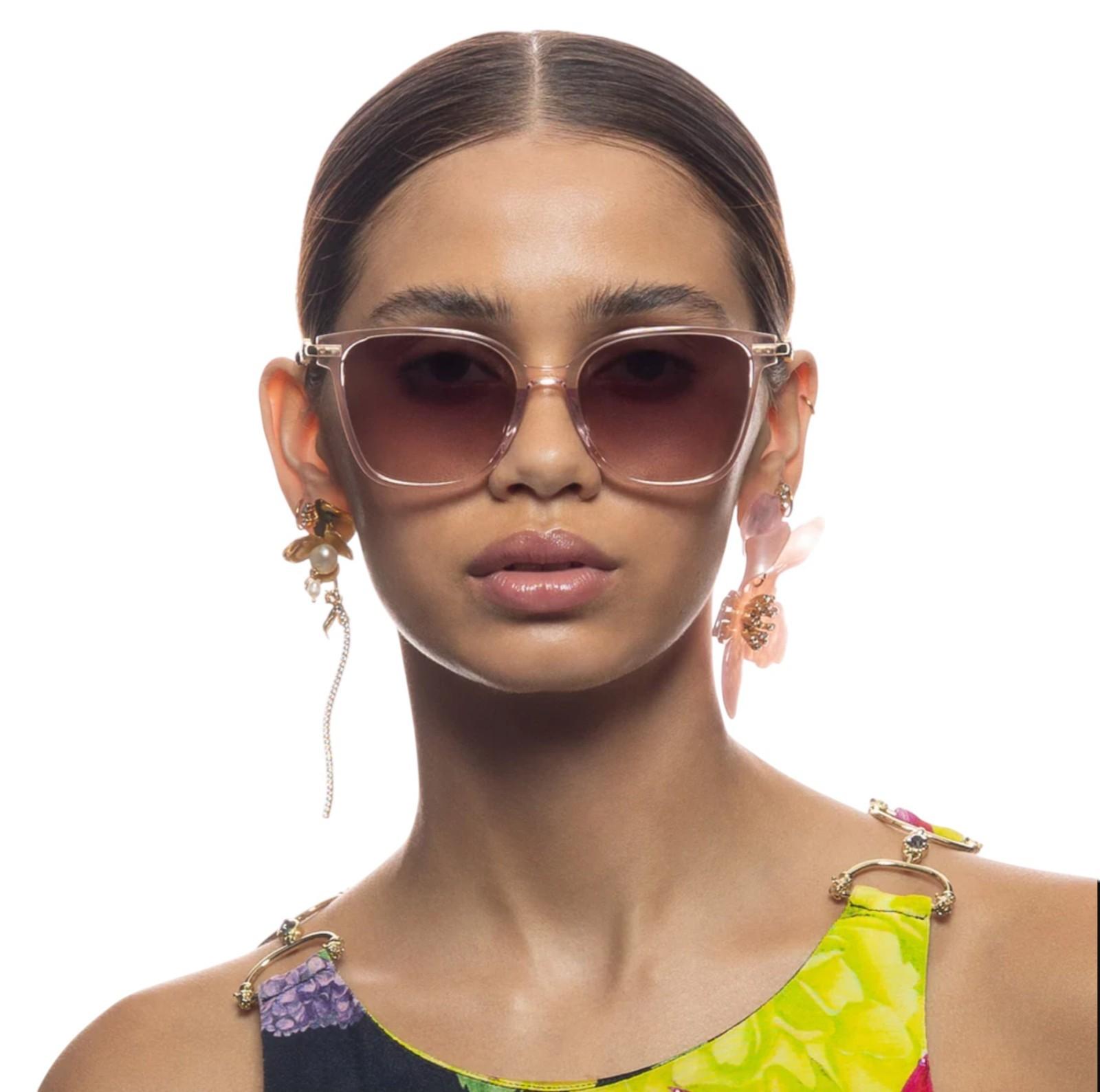 Woman wearing large sunglasses with a colorful top on a white background