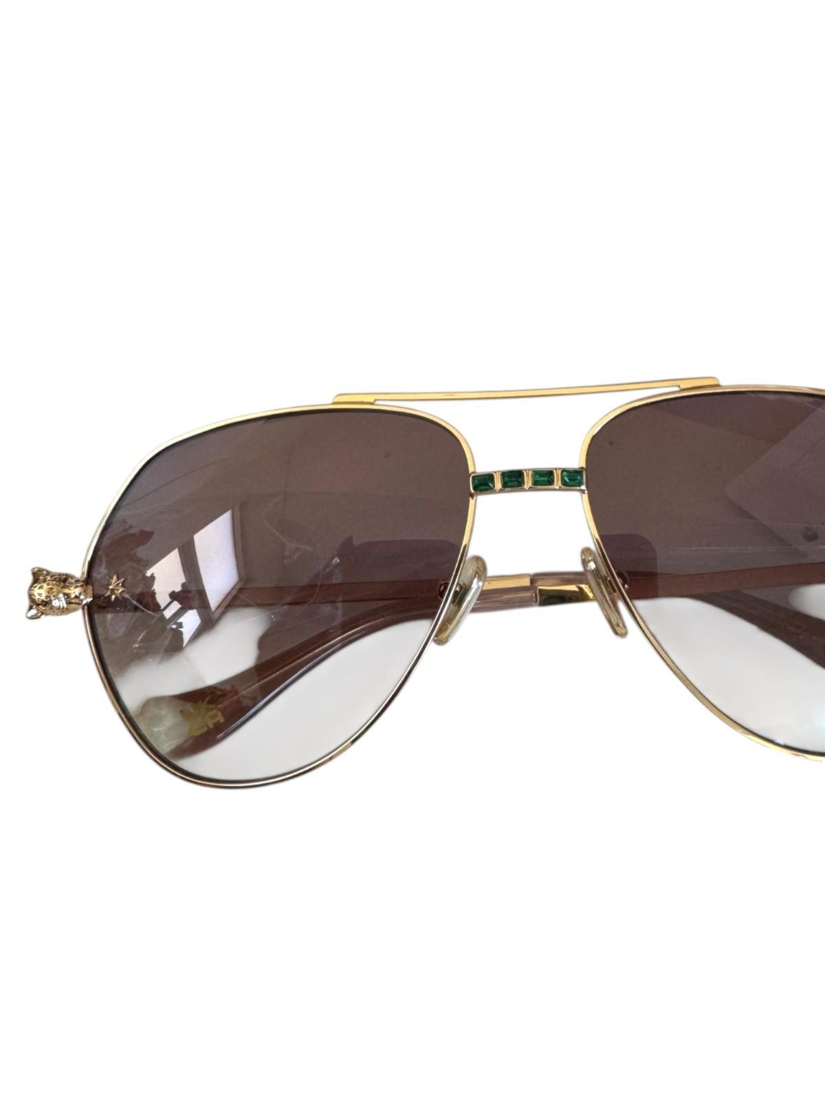 Gold-framed sunglasses with brown lenses on a white background
