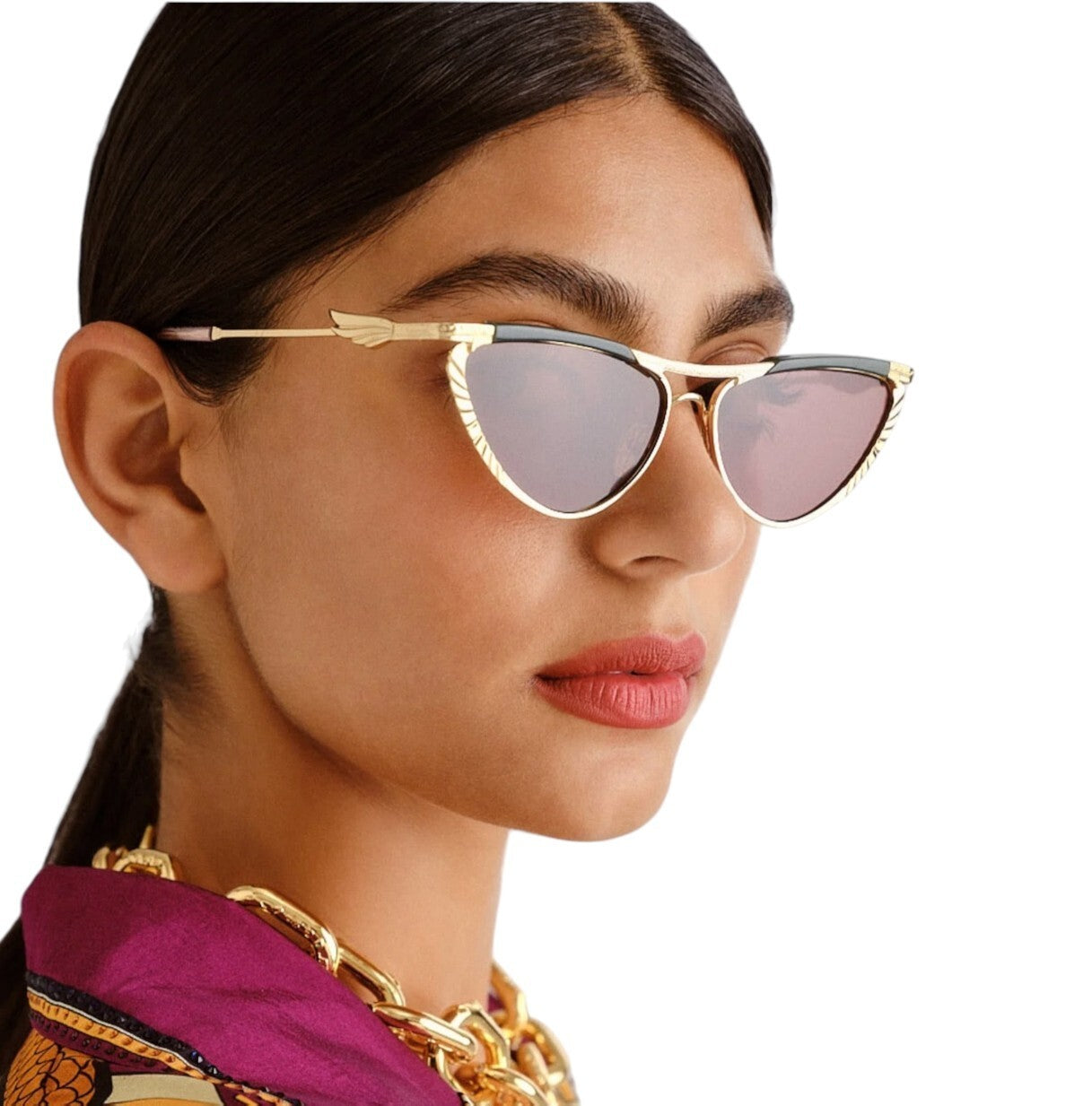 Woman wearing gold-framed sunglasses with pink-tinted lenses on a white background