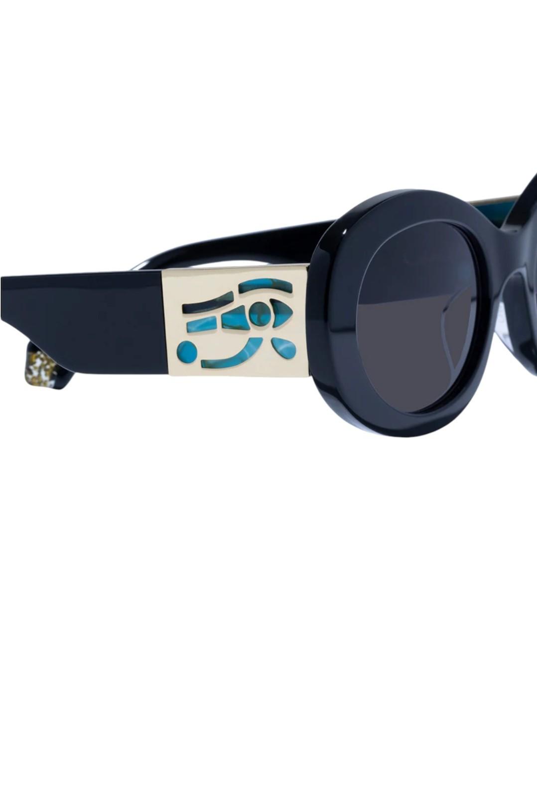 Black sunglasses with a decorative band featuring an eye design on a white background