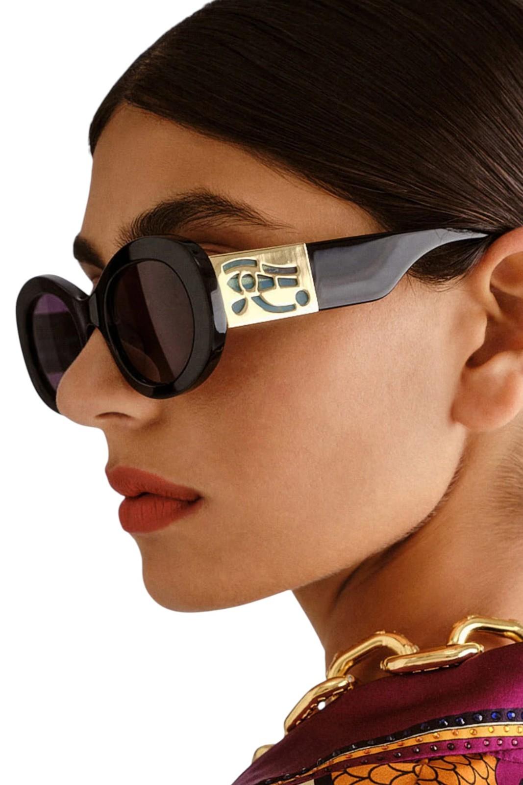 Close-up of a person wearing stylish sunglasses with a gold frame.