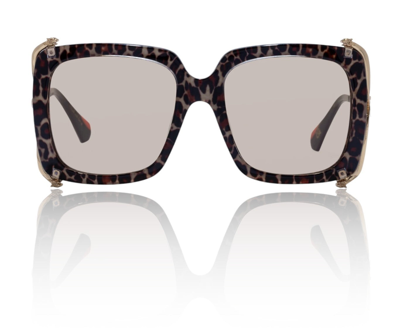Sunglasses with leopard print frame on a reflective surface