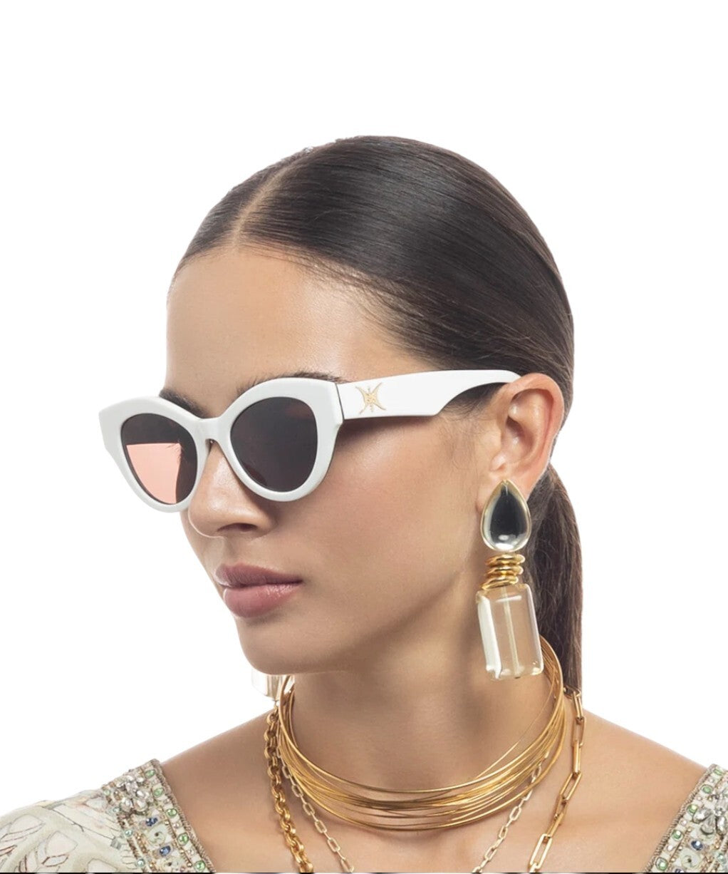 Woman wearing white sunglasses with a gold necklace and earrings on a white background