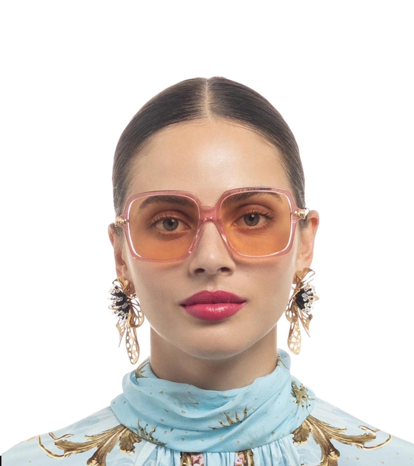 Woman wearing large sunglasses with a plain background