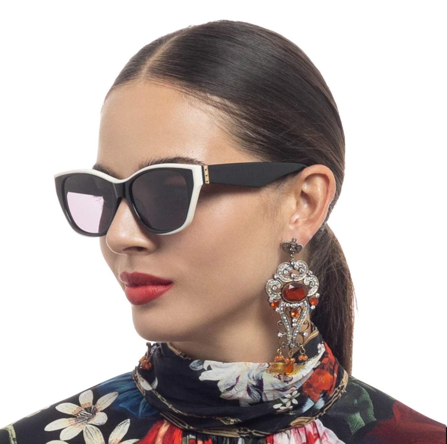 Woman wearing stylish sunglasses and earrings with a colorful outfit on a white background