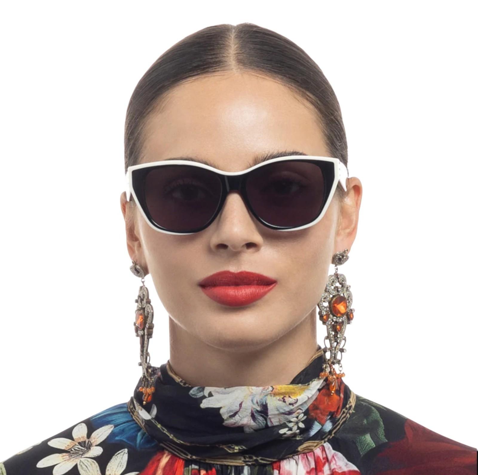 Woman wearing stylish sunglasses and earrings with a colorful scarf on a white background