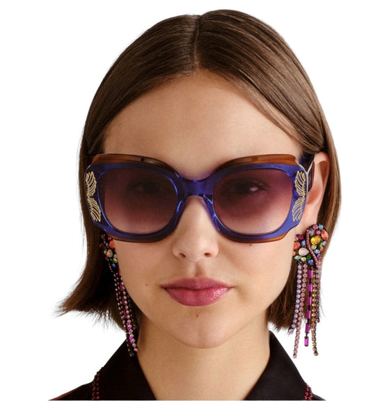 Woman wearing a pair of sunglasses with decorative straps on a white background
