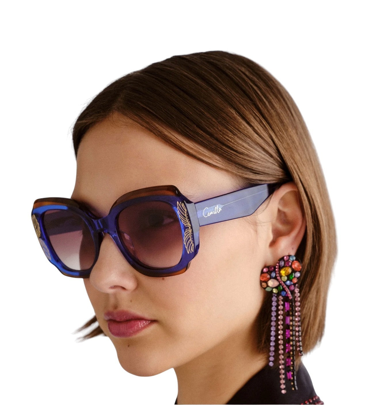 Woman wearing colorful sunglasses and earrings on a white background