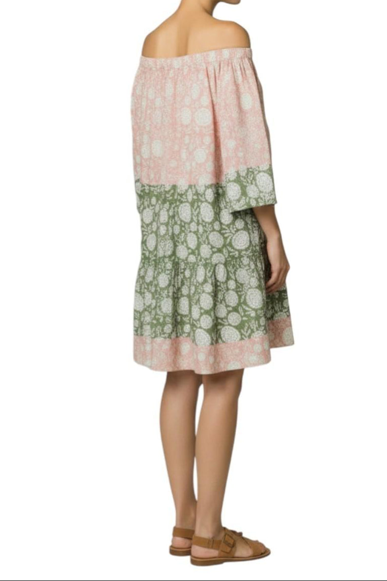 Woman wearing a two-tone dress with pink and green floral patterns on a white background