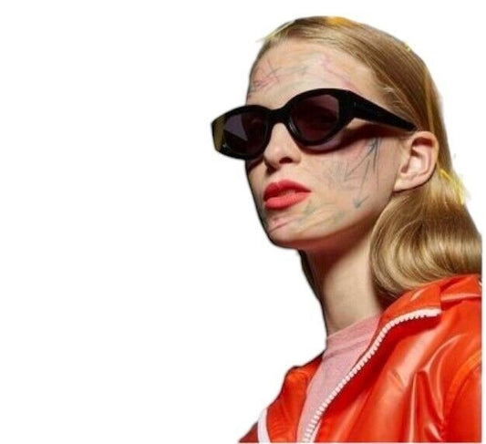 A model wearing Naked Pear Karen Walker Castaway black acetate oval sunglasses with grey smoke lenses and arrow detail