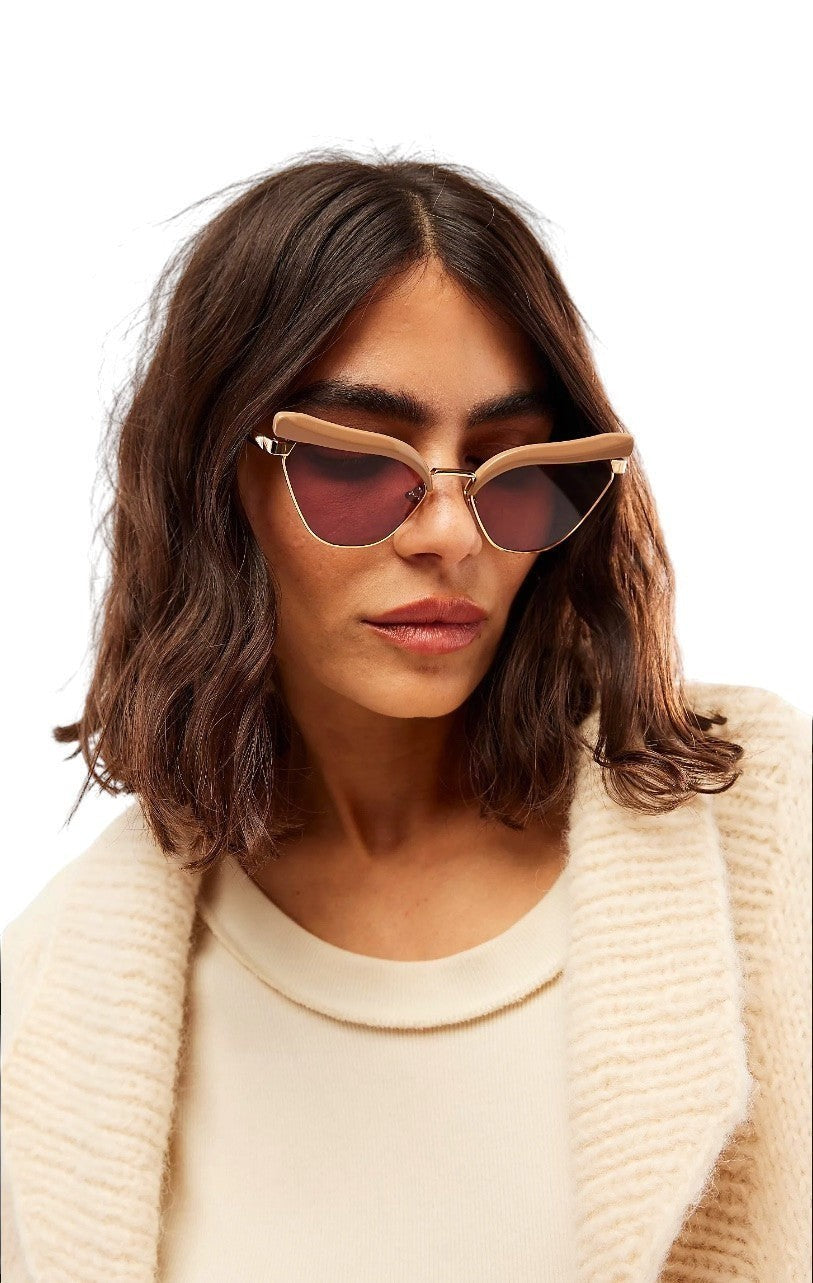 Model wearing Naked Pear Karen Walker Fantasia cat eye sunglasses with taupe acetate, gold metal, and maroon lenses.