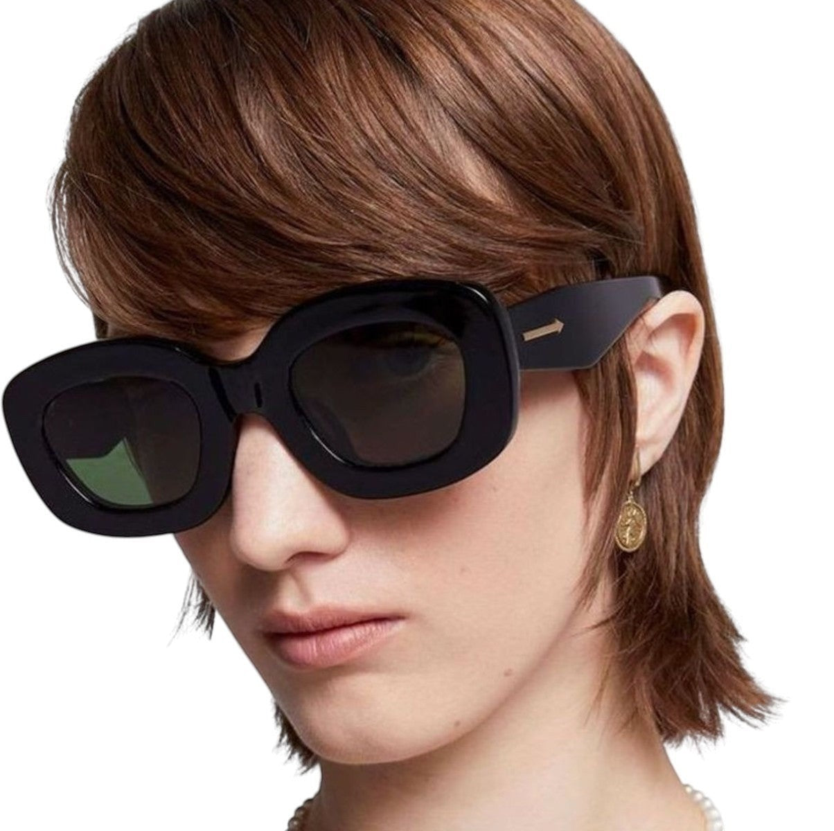 Model wearing Naked Pear Karen Walker Field Trip sunglasses with chunky black bio-acetate frames and green lenses.