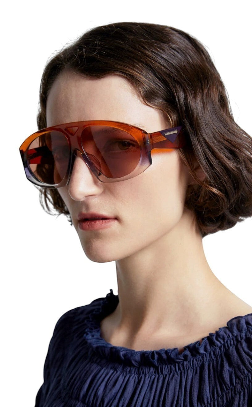 Model wearing Naked Pear Karen Walker Marquise aviator sunglasses in sunset acetate with persimmon-tinted lenses.