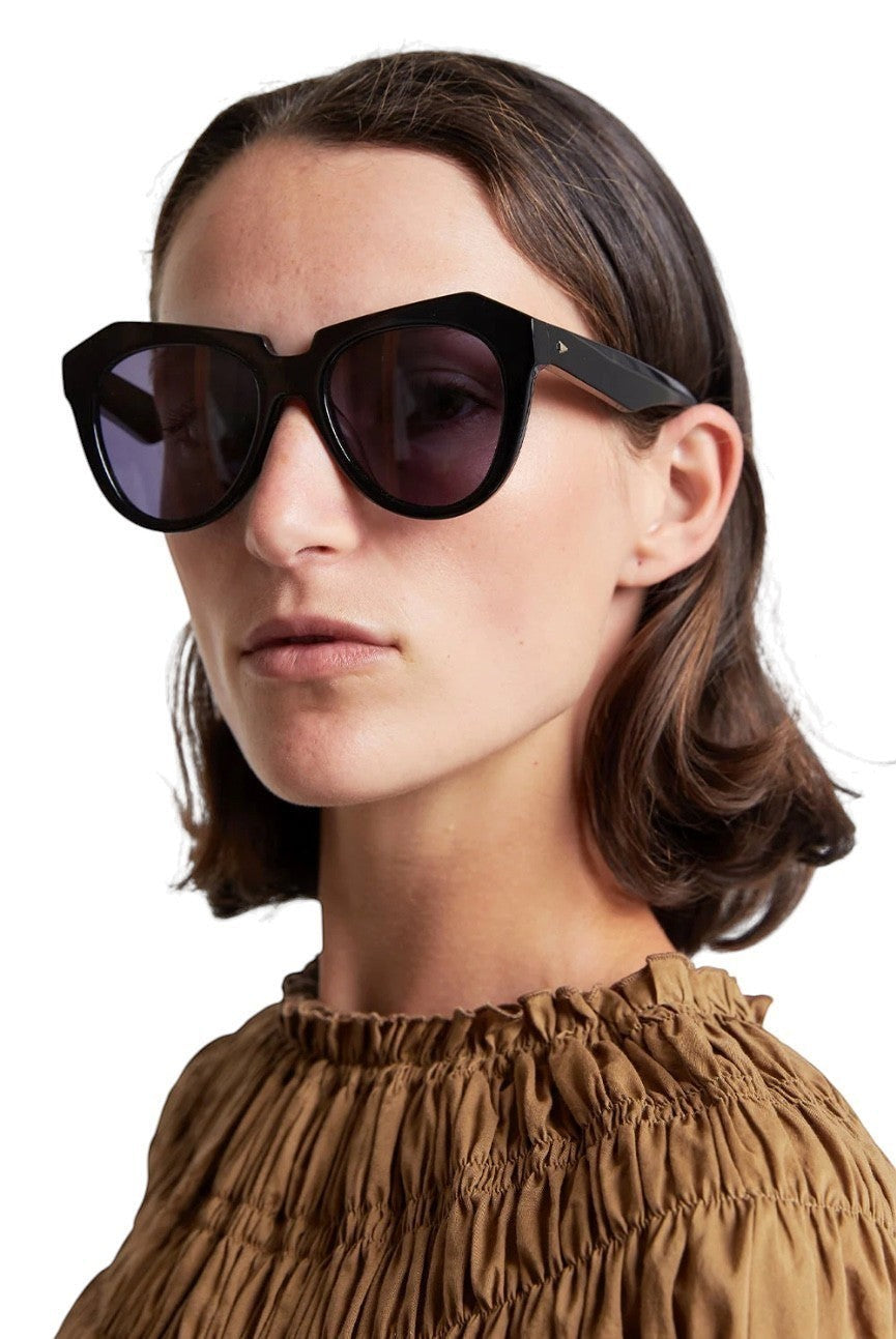 Model wearing Naked Pear Karen Walker Number One black bio-acetate cat-eye sunglasses with grey smoke mono lenses.