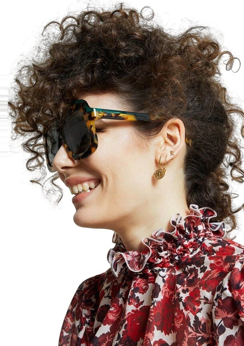 Naked Pear Karen Walker Overdaze sunglasses in crazy tortoise shell acetate with green lenses worn by a smiling woman